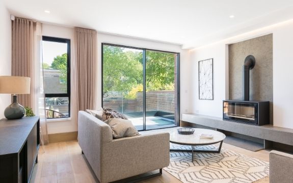 neutral tone living room with a two pane sliding glass door leading to a balcony and a casement window