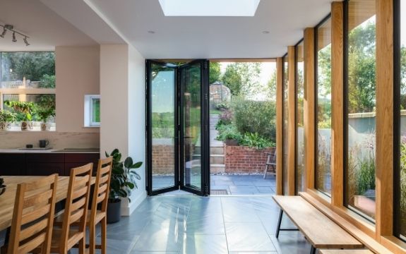 three pane black bifold door with tall fixed casement windows