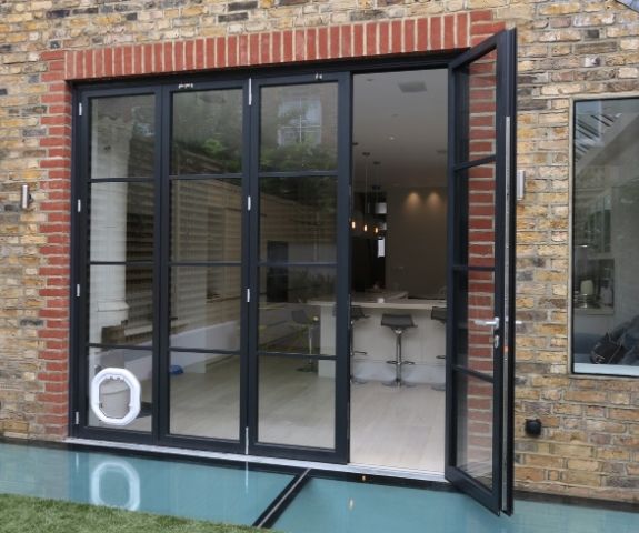 external view of an aluminium bifold door with black frames and a white cat flap