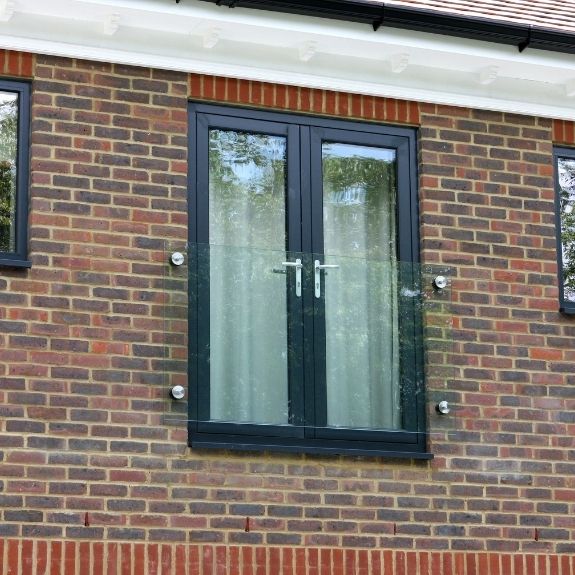 external view of double inward opening casement doors in a french door design with a frameless glass juliet balcony for a modern look