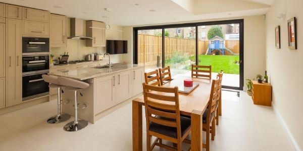 slim sliding glass door in a contemporary kitchen extension that has warm neutral tones