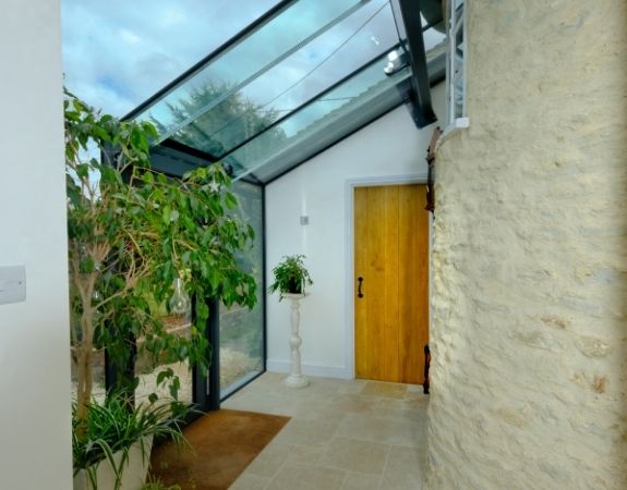 contemporary glass extension on an English cottage with invisio glass roof and large houseplants to create a strong connection to nature
