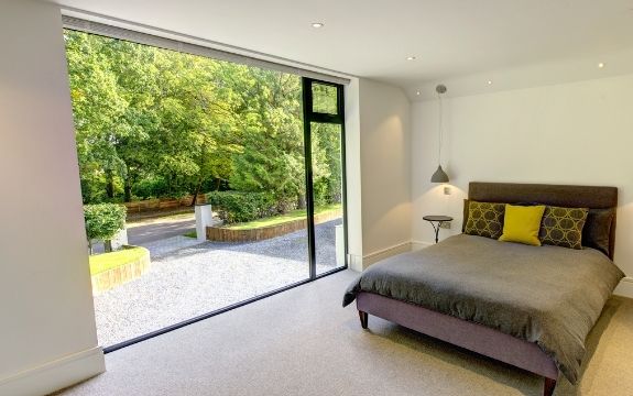 floor to ceiling fixed window with a top hung casement window used to create a glass wall that lets natural light into this bedroom