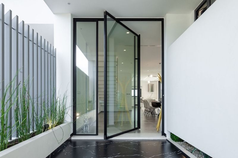 Sieger Lux Pivot Door with slim aluminium framing, a large pull handle and a fixed sidelight